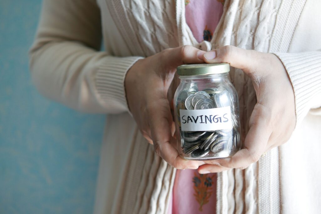 someone holding a jar full of coins for saving
