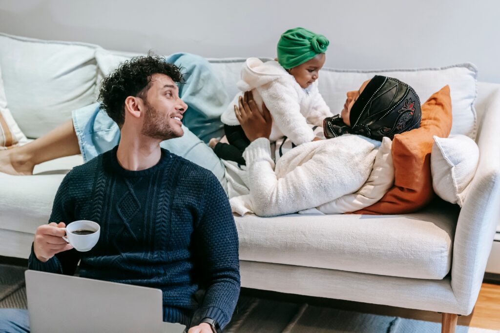 happy family of three, a man his partner and daughter playing on couch