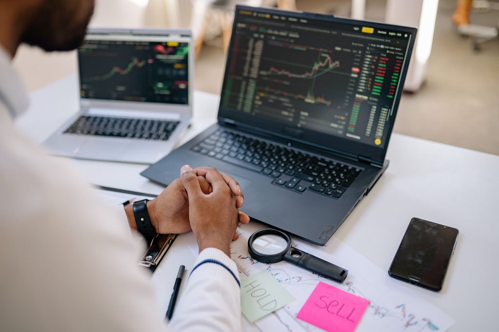 How to Buy Your First Index Fund someone sitting in front of a laptop with trading charts on the screen